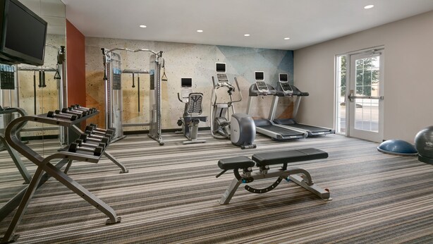 A gym with treadmills, weight machines, and a bench.