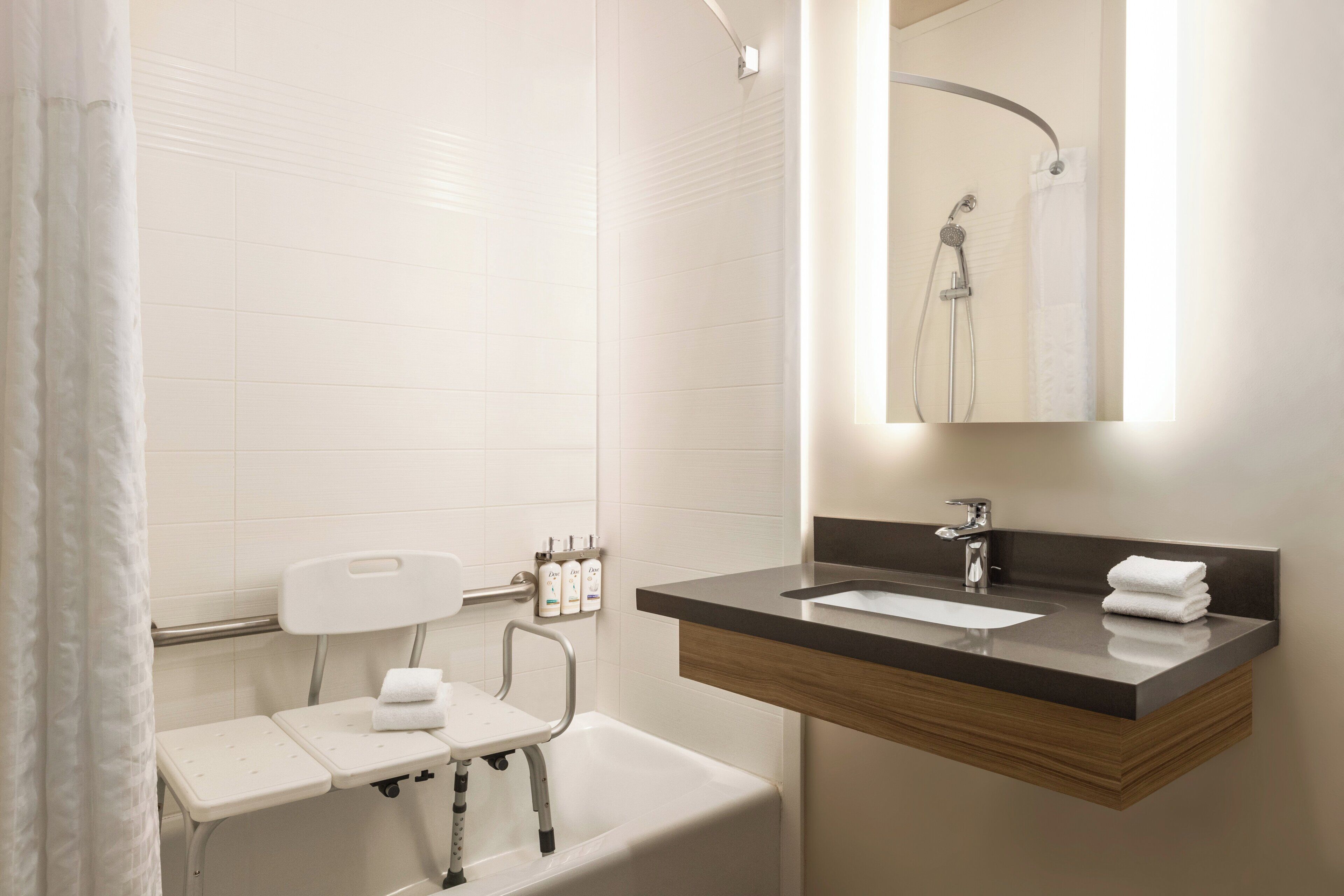 A modern bathroom with a bathtub, a vanity with a mirror, and a shower.