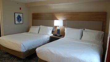 A hotel room with two beds, a nightstand, a lamp, and a framed picture on the wall.