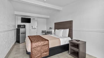 A hotel room with a bed, bedside table, and a small desk with a chair.