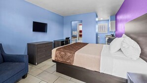 A hotel room with a bed, a desk, a dresser, and a TV on the wall. - American Executive Inn (Mesa)