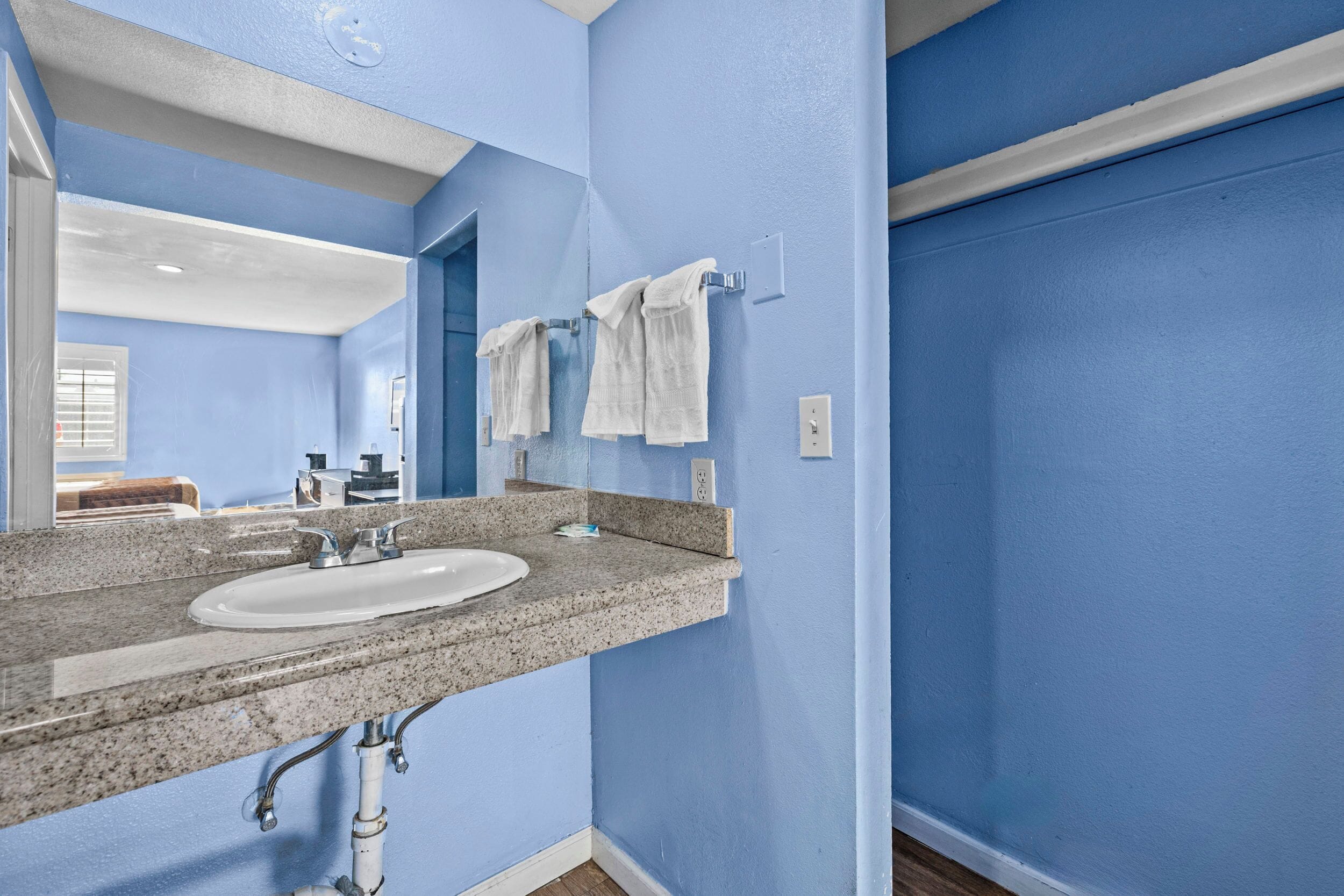 A bathroom with a white sink, blue walls, and a mirror.
