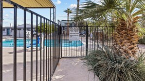 A gated pool area with a sign detailing pool rules, including hours and no smoking policy. - American Executive Inn (Mesa)