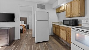 A modern kitchen with white appliances, wooden cabinets, and a built-in microwave. - American Executive Inn (Mesa)