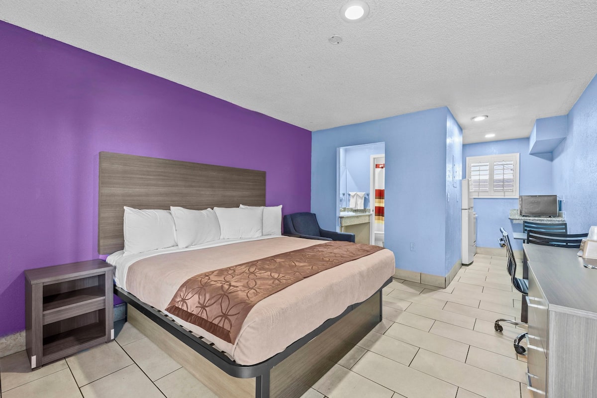 A hotel room with a bed, a desk, and a chair.