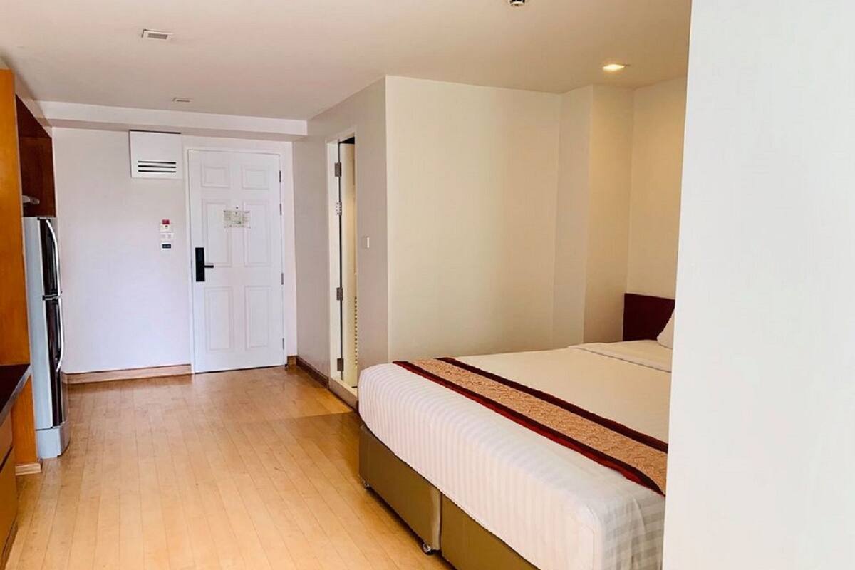 Una camera d'albergo con un letto, un armadio, una porta e un piccolo angolo cottura.