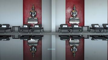 Une pièce dotée d’un sol réfléchissant, de fauteuils noirs et de deux grandes statues de Bouddha, le tout sur un fond de murs rouges.