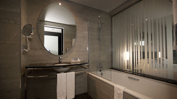 Un baño moderno con un espejo grande, un lavamanos y una bañera.
