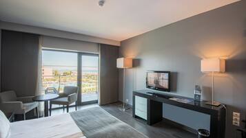 Habitación de hotel con cama, escritorio, televisor y zona de estar.