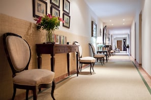 Un pasillo de hotel con piso alfombrado, muebles de madera y cuadros en las paredes.