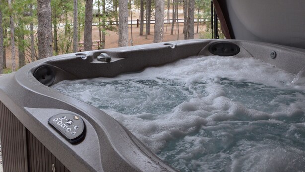 Un jacuzzi con terraza de madera y vista a un bosque.