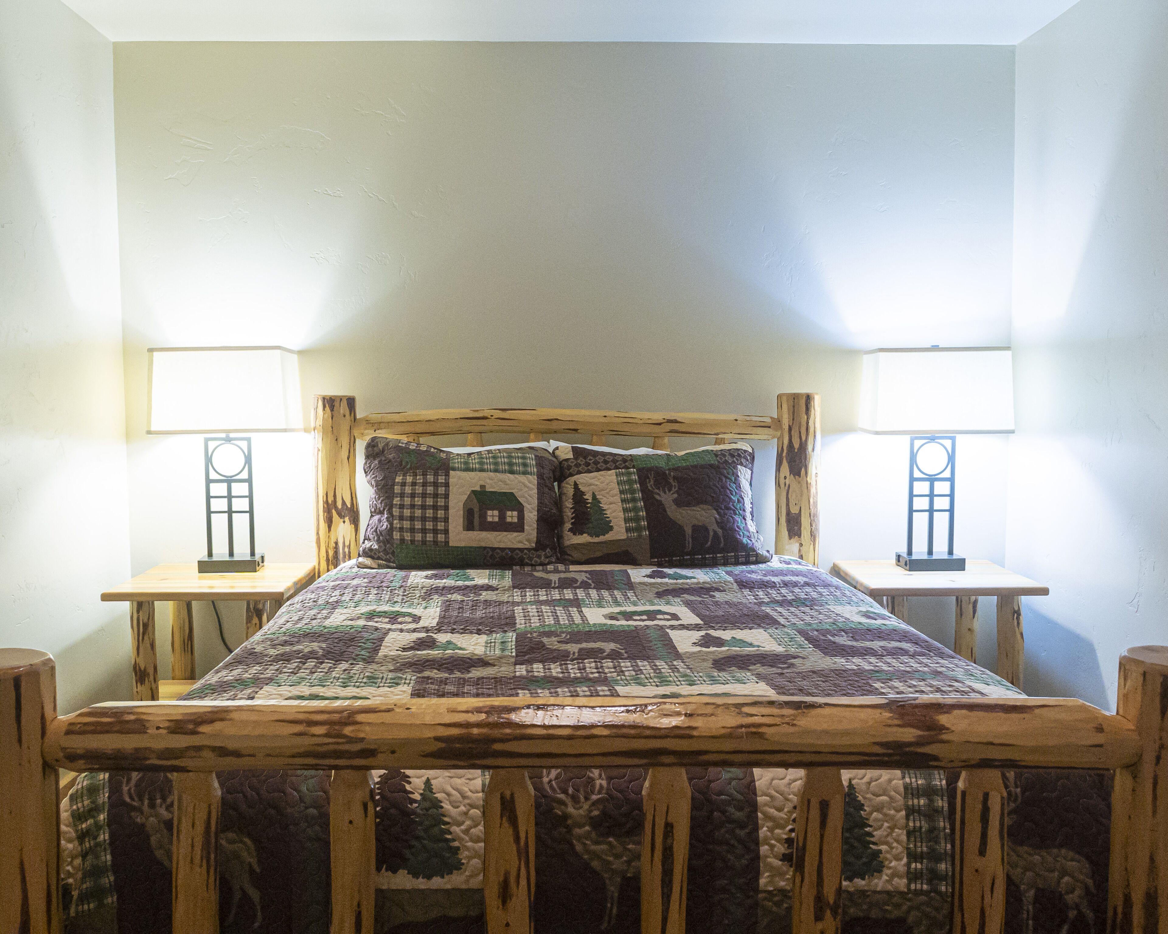 A bed with a wooden headboard, two bedside tables, and two wall-mounted lamps.