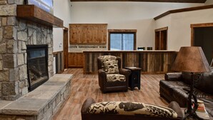 Amplia sala de estar con chimenea de piedra, armarios de madera, sofá de cuero y zona de bar.