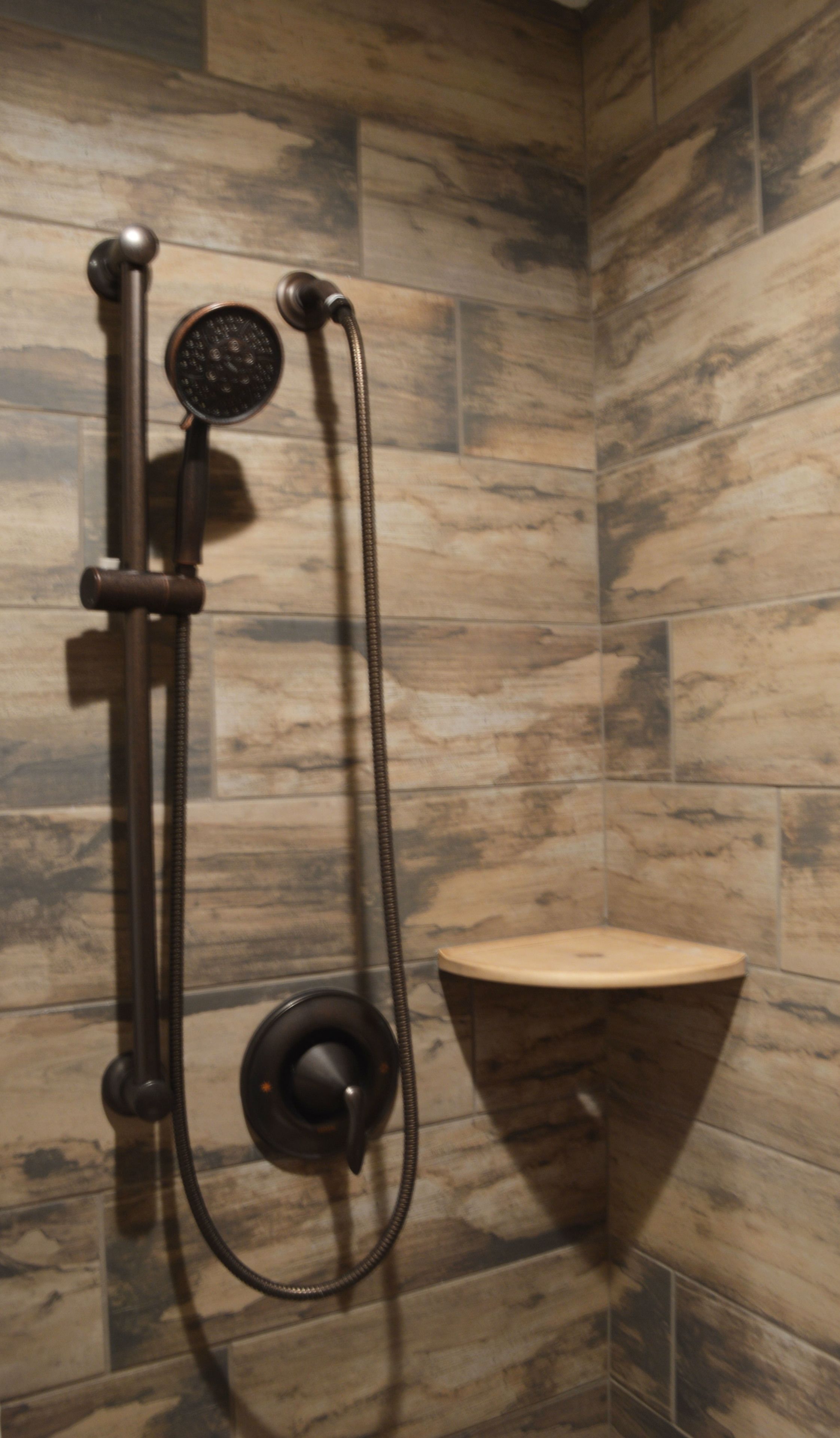 A shower with a handheld showerhead and a wall-mounted control.