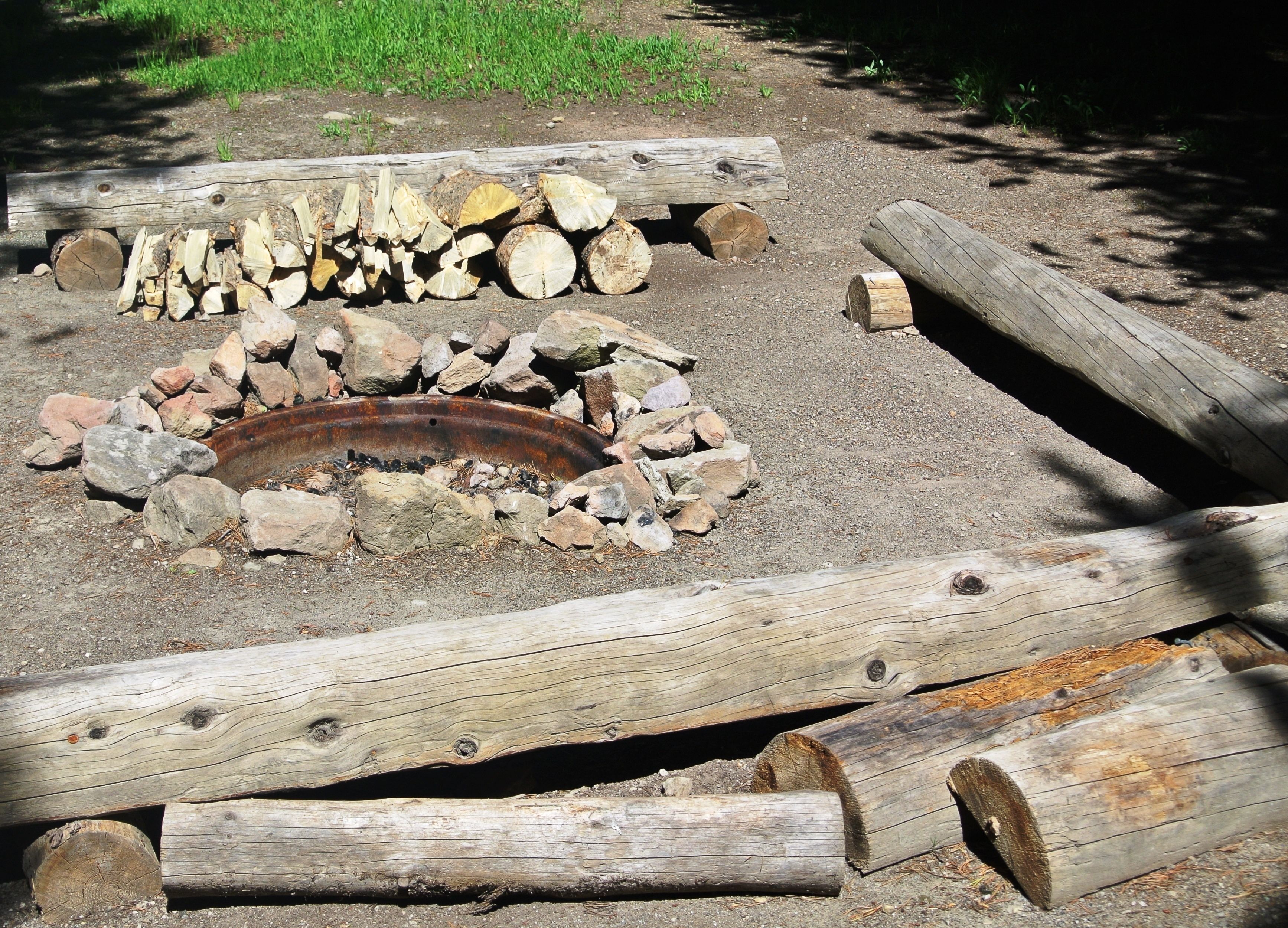 A rustic outdoor fire pit surrounded by logs and rocks.
