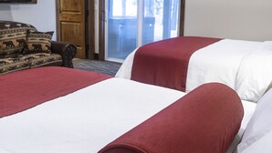 Habitación de hotel con dos camas, un sofá, un televisor y una puerta que da a un balcón.