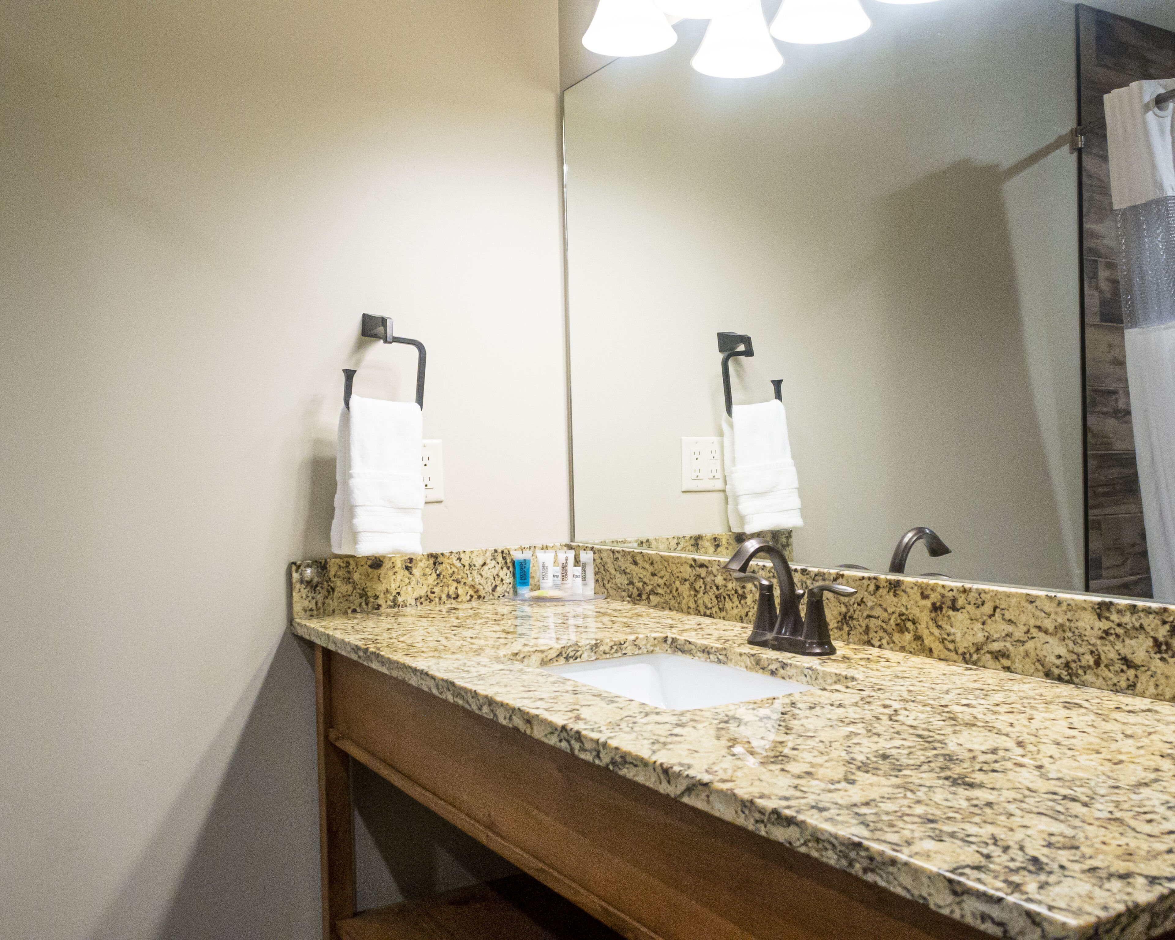 A bathroom with a granite countertop, two sinks, and a large mirror.