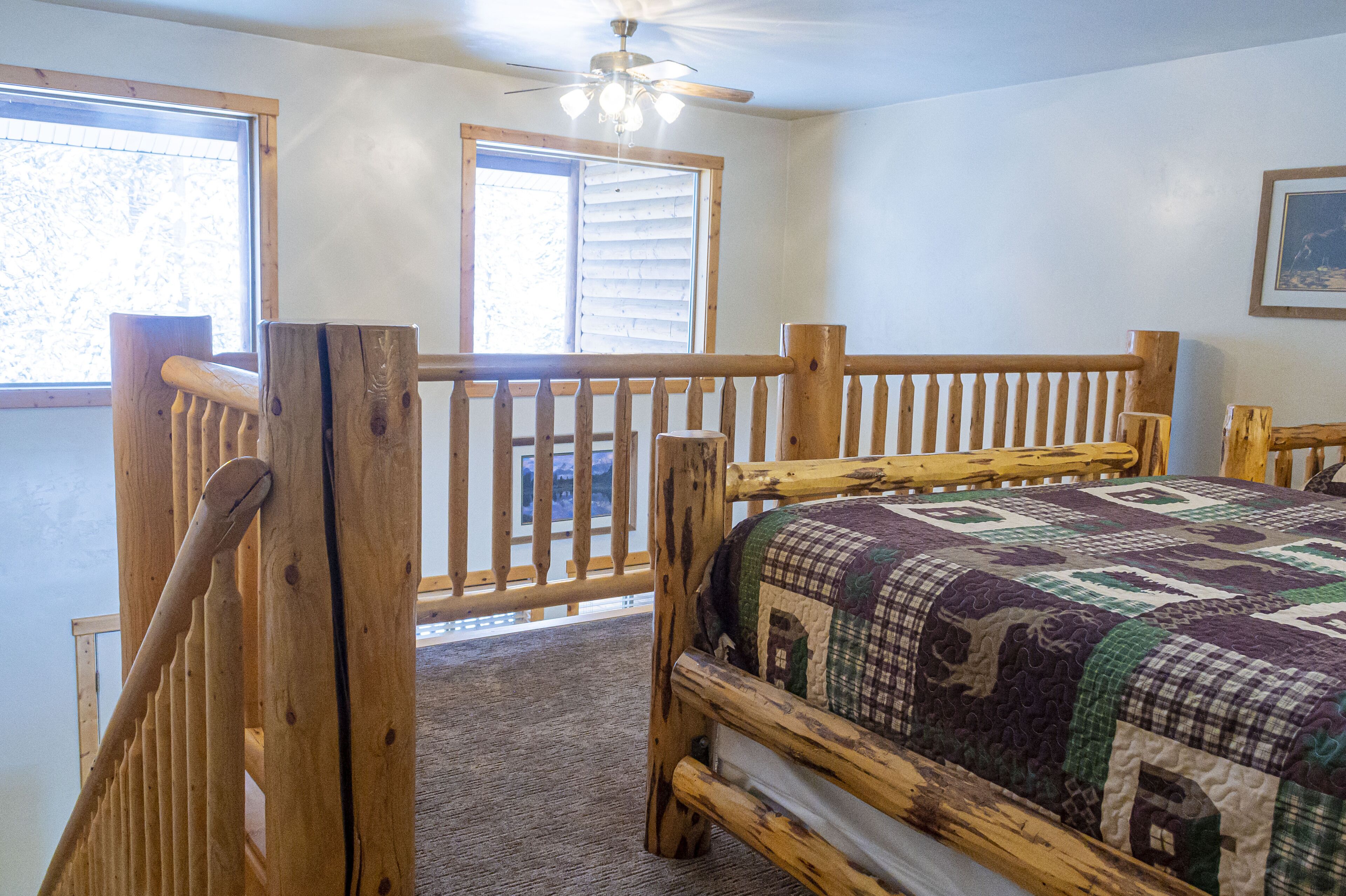A bedroom with a wooden bed frame, a quilt, and a window with blinds.