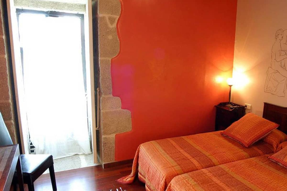 A room with a bed, a nightstand, a lamp, and a partial view of a wall with a drawing.
