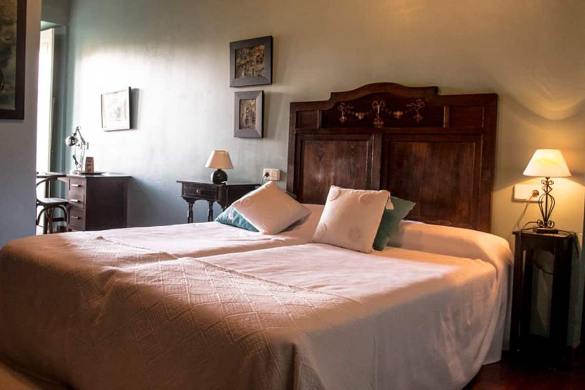 A double bed with a wooden headboard, two bedside tables with lamps, and a desk with a chair.