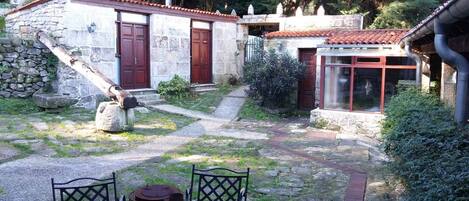 Un edificio in pietra con tetto in tegole rosse, una porta in legno e una piccola finestra.