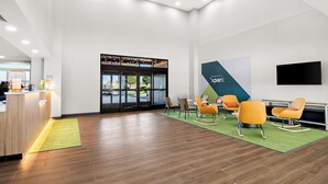 Um hall amplo com balcão de recepção, área de estar e uma janela grande com vista.