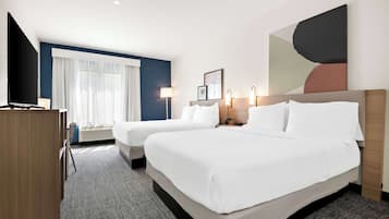 Une chambre d’hôtel avec deux lits, un bureau, une télévision et un grand tableau abstrait accroché au mur.