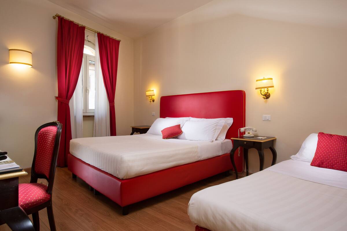 A hotel room with two beds, a desk, and a chair.