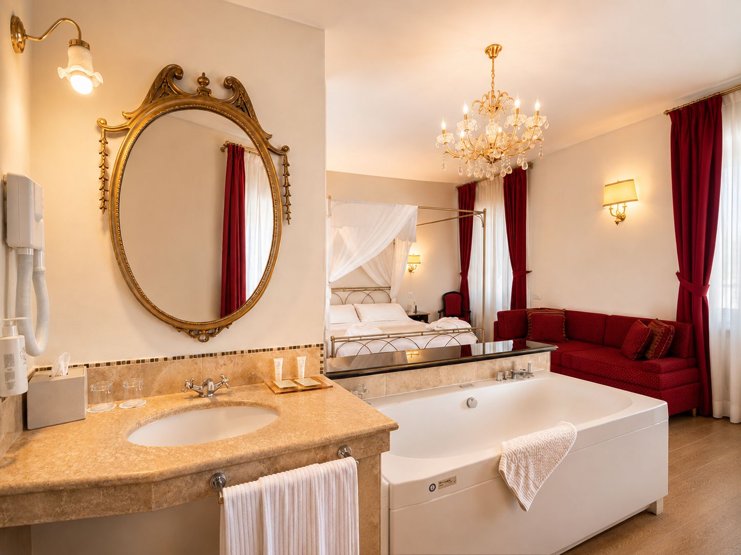 A hotel room with a large mirror, a bathtub, a sofa, and a chandelier.