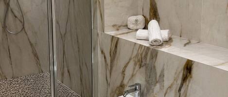 A modern bathroom with a glass-enclosed shower, a bidet, and a toilet.
