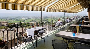 Una terraza con mesas y sillas, con vistas a un paisaje pintoresco.