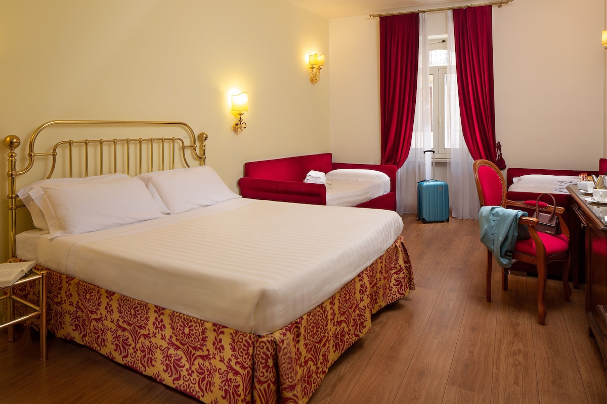 Habitación de hotel con cama, escritorio, silla y maleta.