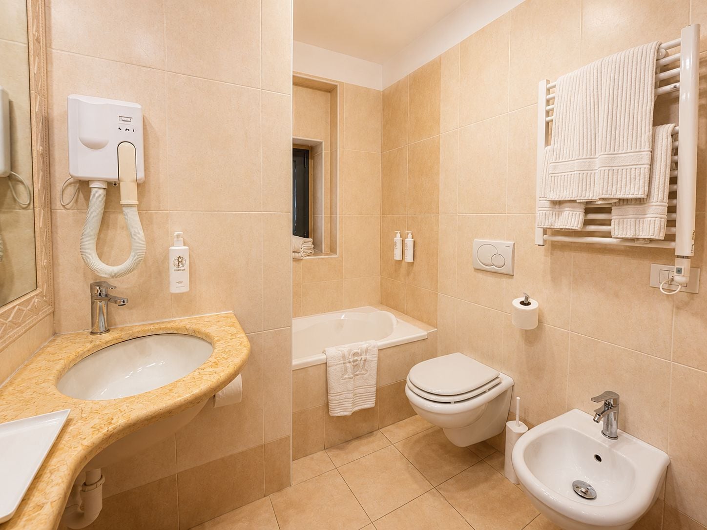 Ein Badezimmer mit Waschbecken, Toilette, Bidet und Handtuchhalter.
