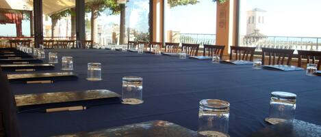 A dining area with tables set for a meal, clear glass candle holders, and a view of the outdoors.