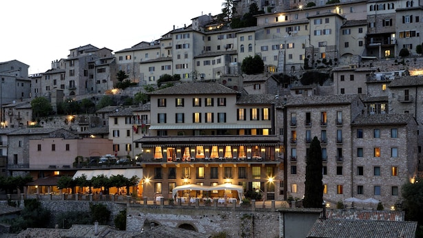 A historic hotel with multiple floors, outdoor seating, and a stone facade. - Giotto Hotel & Spa (Assisi)
