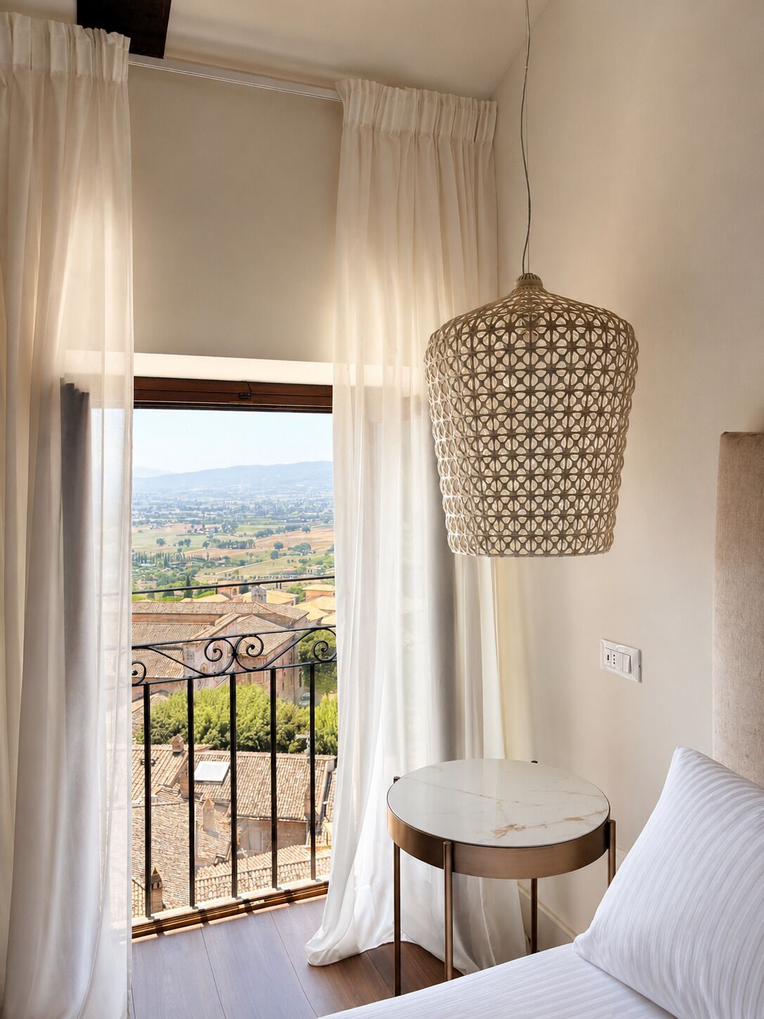 Ein Balkon mit Blick auf eine Landschaft, ein runder Tisch und eine Pendelleuchte.