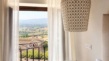 Ein Balkon mit Blick auf eine Landschaft, ein runder Tisch und eine Pendelleuchte.
