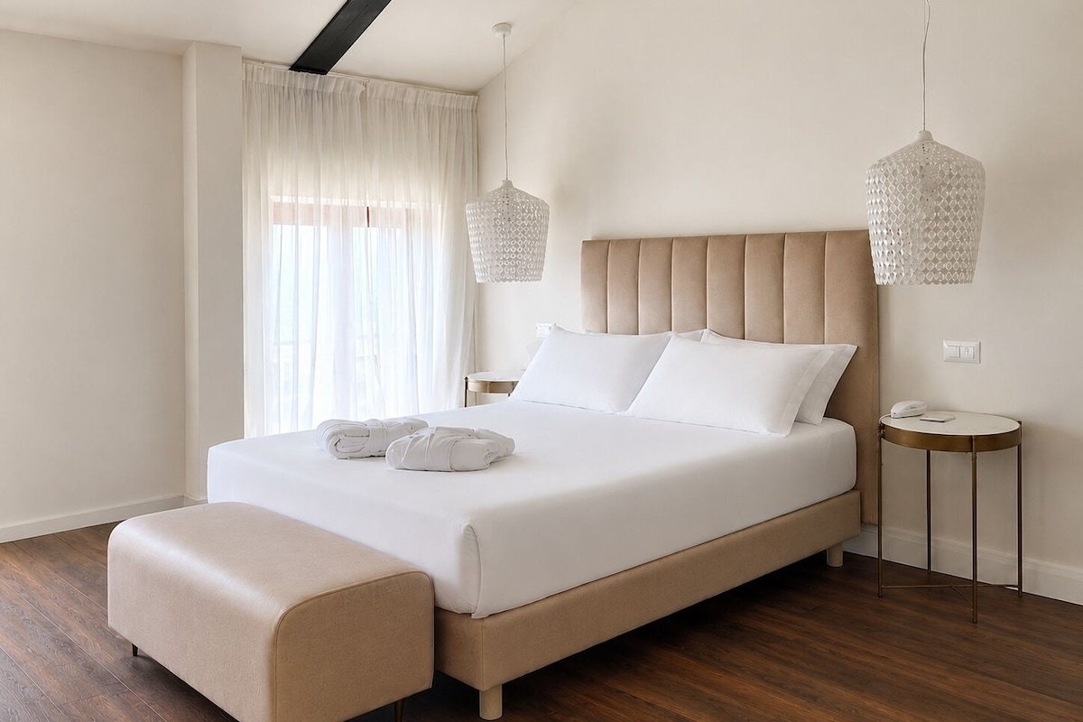 Una habitación de hotel moderna con una cama grande, una mesita de noche y una lámpara colgante.