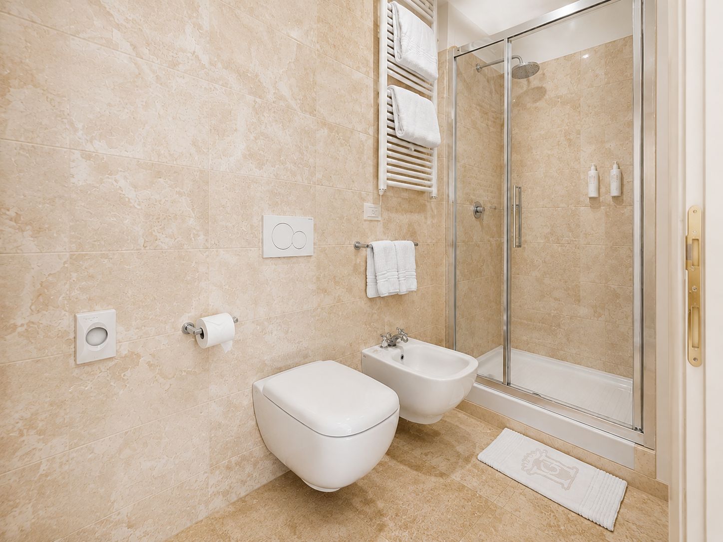 Un baño moderno con inodoro, bidé y ducha con mampara de vidrio.