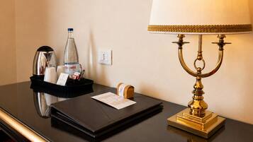 A hotel room desk with a black tray holding a water bottle, a coffee maker, and a notepad.