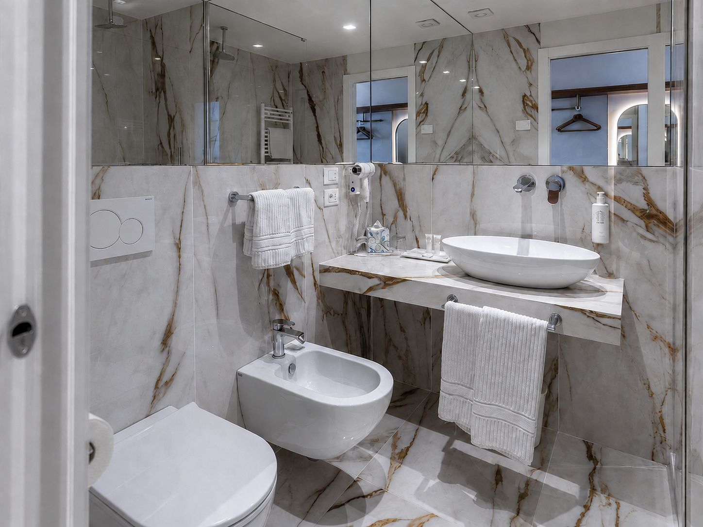 A modern bathroom with a bidet, toilet, and a large vanity with a sink.