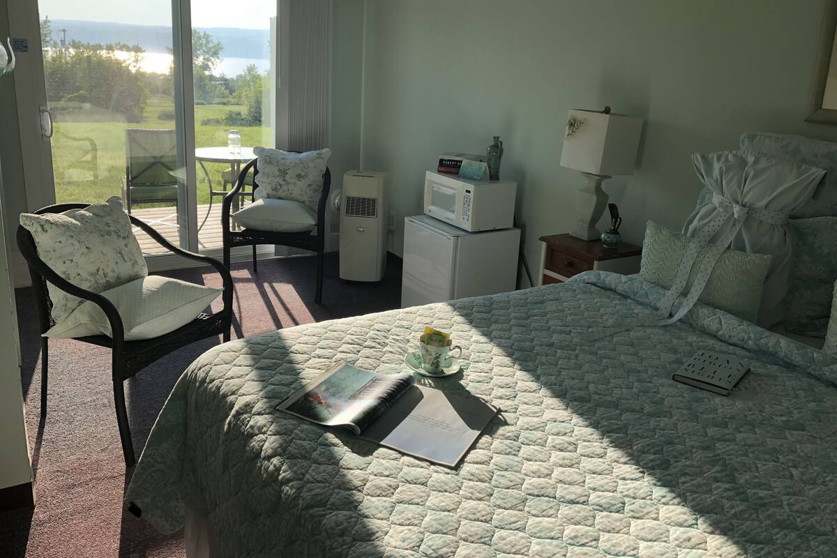 Habitación de hotel con cama, una silla, una mesita y vistas al exterior.