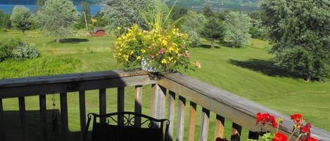 A wooden deck with a metal chair and a flower pot with yellow and pink flowers.