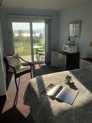 Et hotelværelse med seng, stol, skrivebord med mikroovn, lille køleskab og udsigt til det fri.