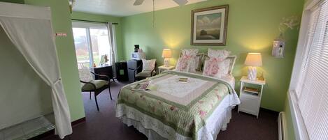 A bedroom with a bed, a desk, a chair, a ceiling fan, and a window with blinds.