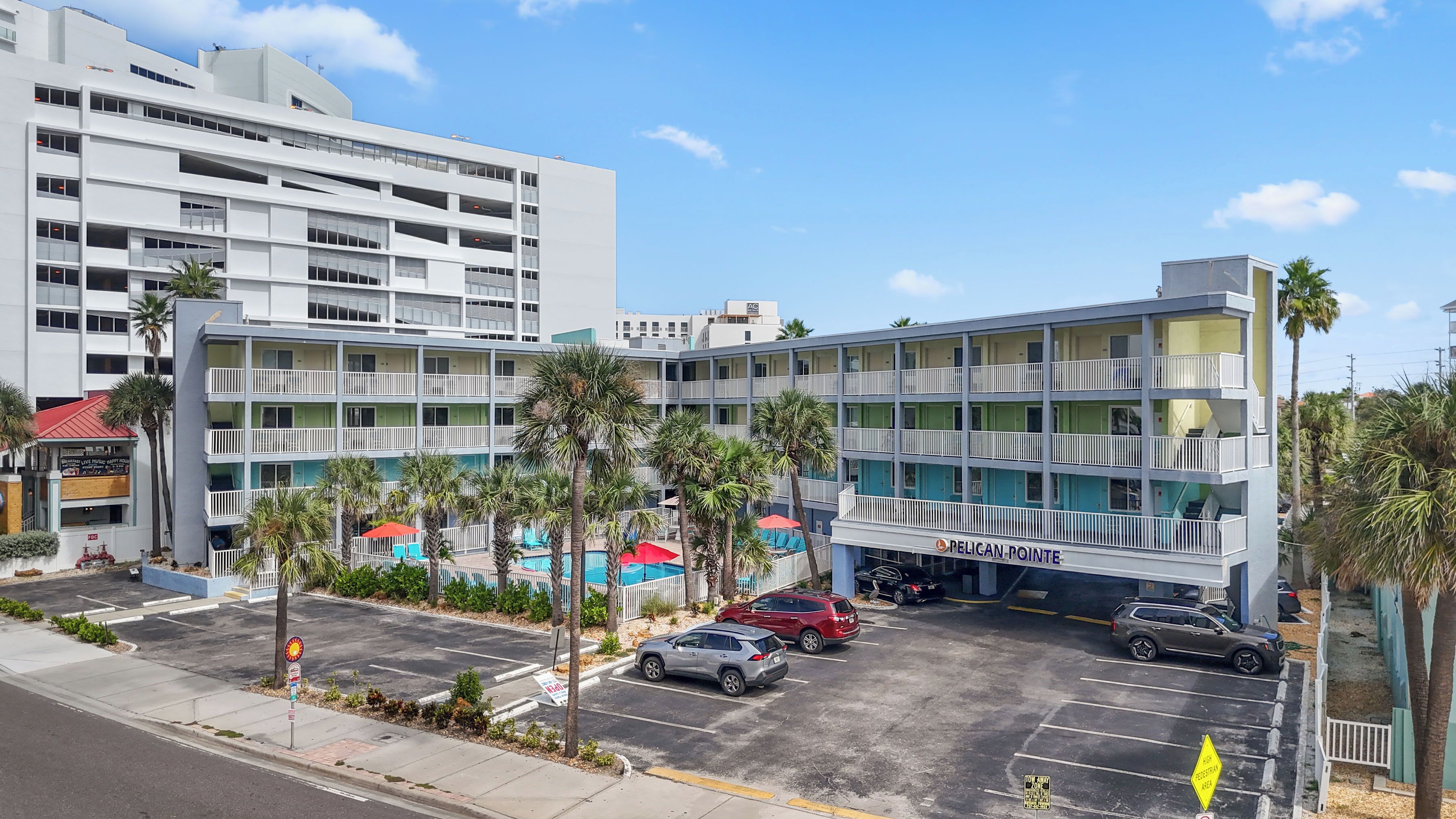 A multi-story hotel with a pool area, parking, and a view of the surrounding cityscape.