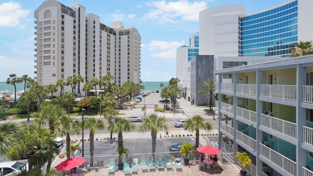A hotel with a pool area, palm trees, and a view of the ocean.