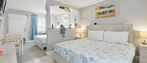Ett sovrum med en säng, ett skrivbord och en stol. Det finns en dörr med texten ”Stranden” och en målning som föreställer en strandscen.