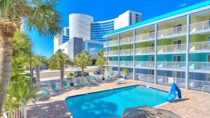 A hotel with a pool, palm trees, and a modern building in the background.