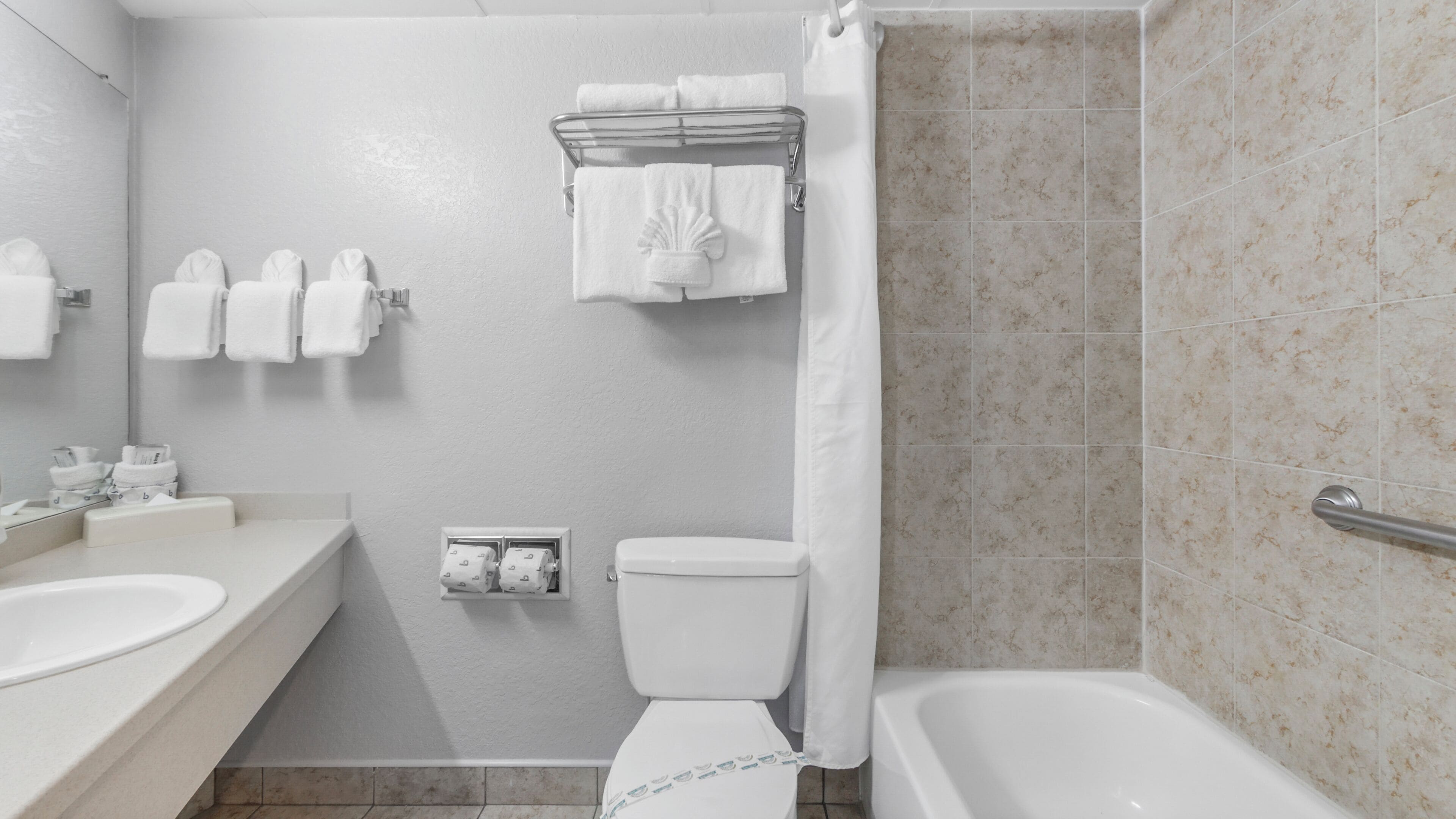 Une salle de bain avec une baignoire, des toilettes et un lavabo. Plusieurs serviettes sont suspendues sur un porte-serviettes.
